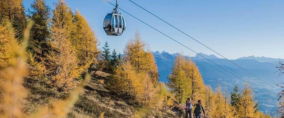 https://www.hotel-edelweiss.it/media/2bea15e6-8599-49c7-9464-8e95dcbeade9/958_x_400/zwei-wanderer-gehen-durch-goldgelbe-laerchenwaelder-waehrend-ueber-ihnen-eine-moderne-seilbahngondel-schwebt.jpg